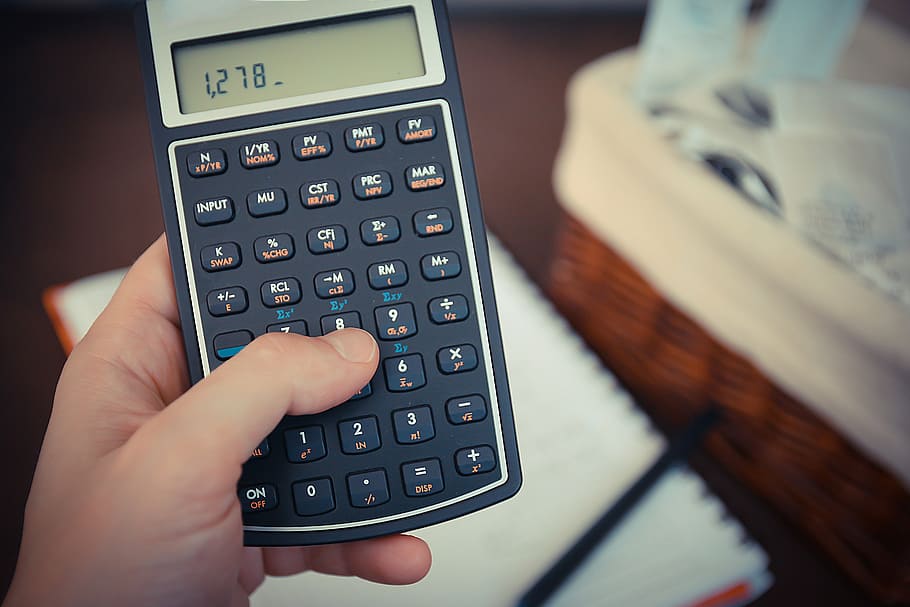 A close-up of a hand holding a calculator with financial calculations.